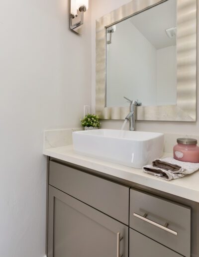 Modern bathroom vanity with a rectangular sink, a light fixture above a framed mirror, and a pink candle on the counter.